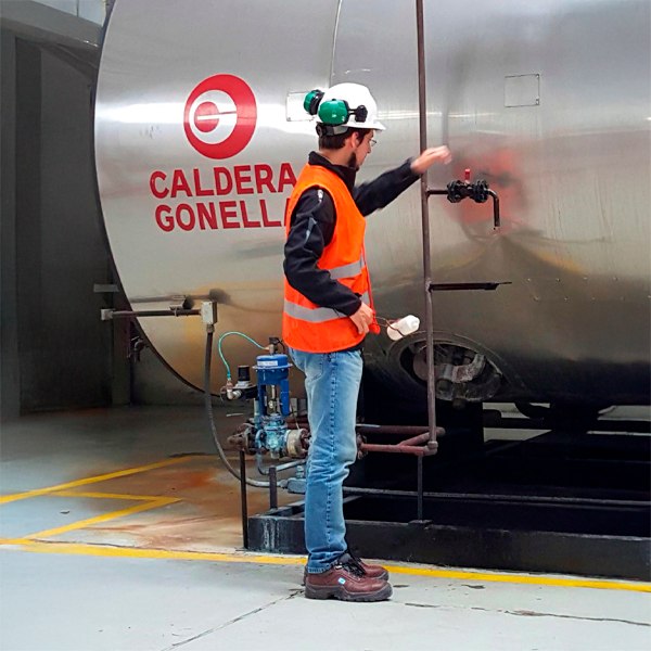 Técnico inspeccionando un sistema industrial de caldera y vapor